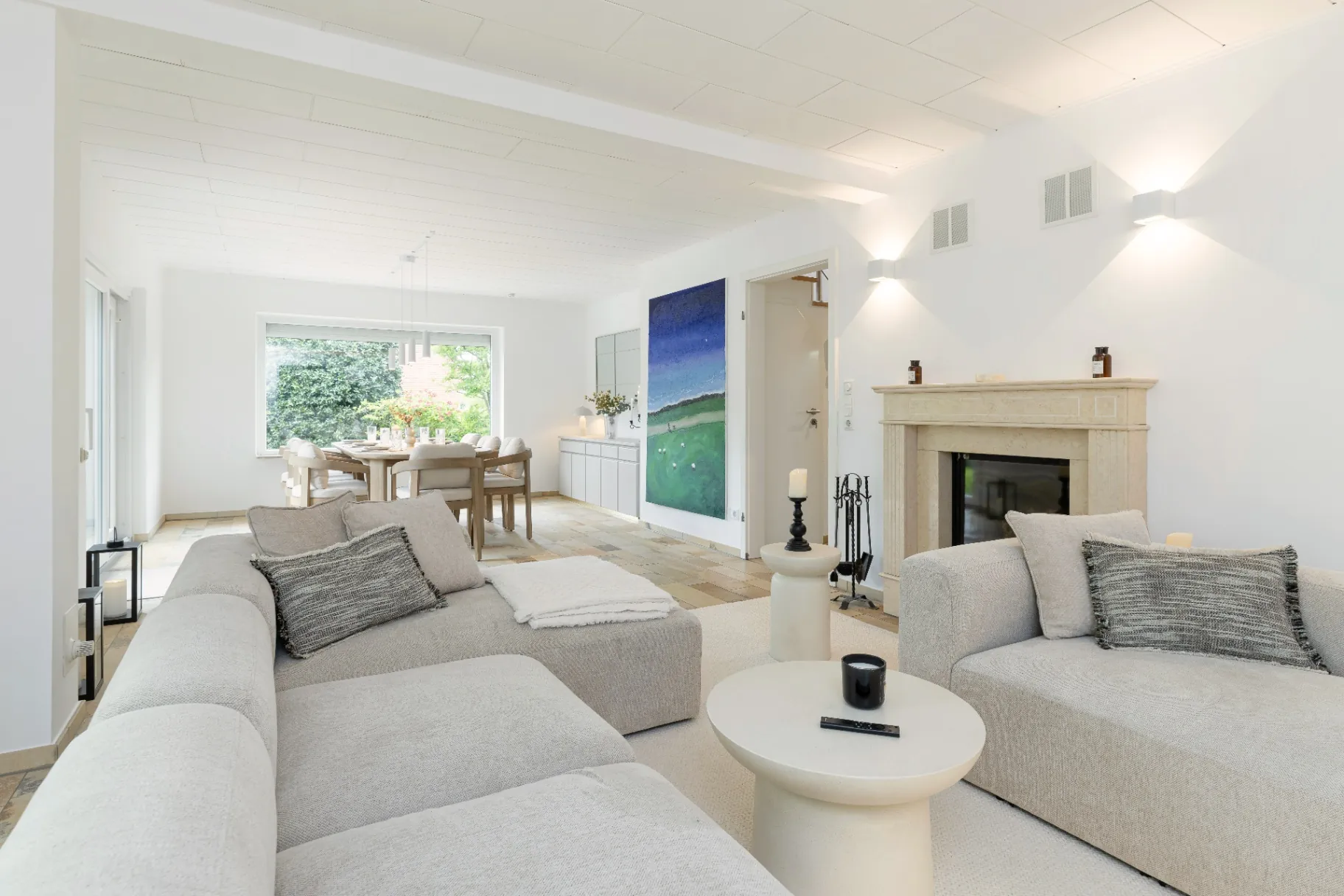Wohnbereich mit Kamin, Kunstwerk und Esszimmer im Hintergrund im Ferienhaus Smukke in Nordfriesland