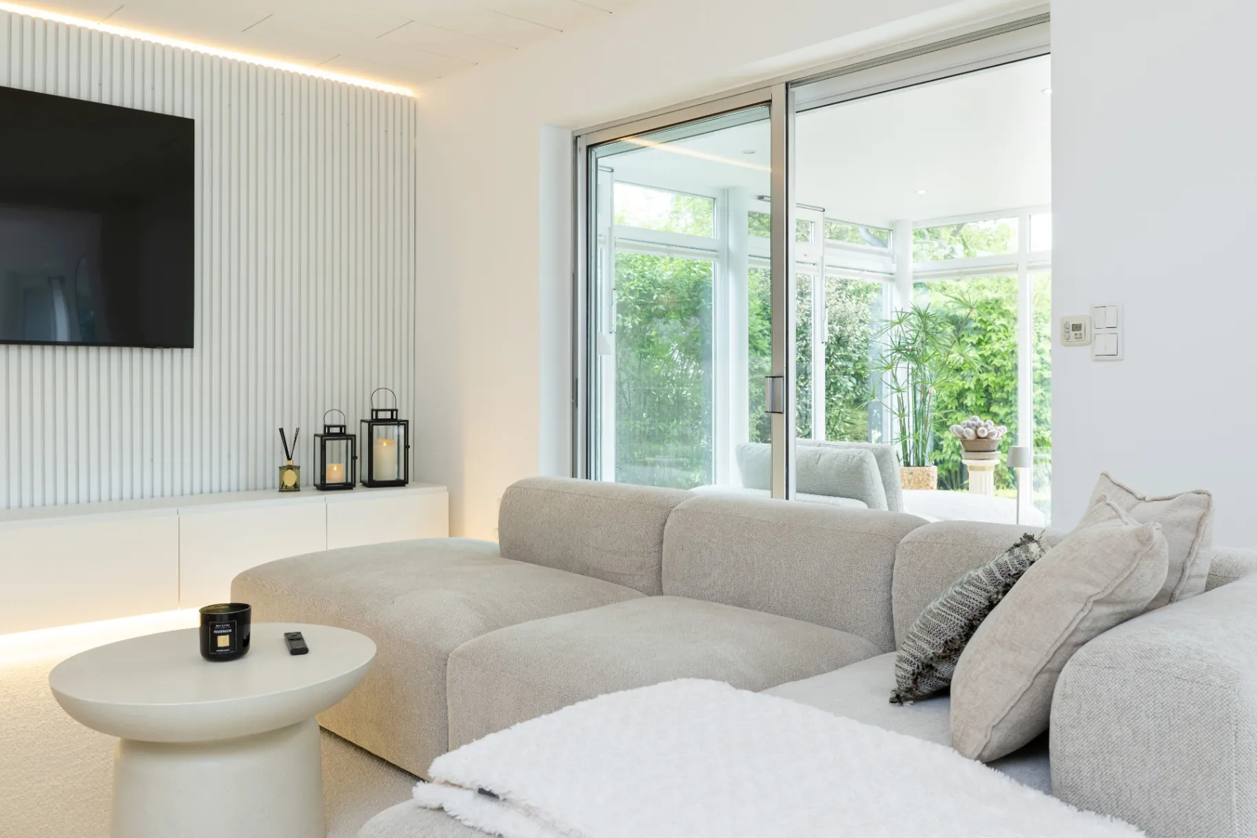 Großes Loungesofa mit Blick durch Glasfront in den Wintergarten im Ferienhaus Smukke in Hattstedt